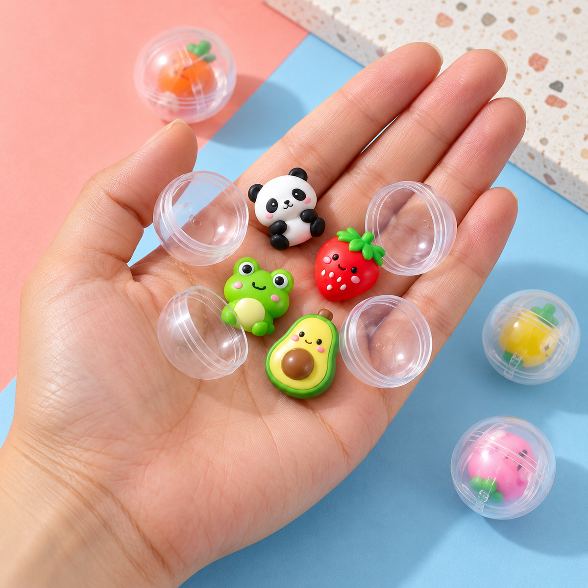 Adult hand holding tiny panda frog strawberry and avocado capsule surprises